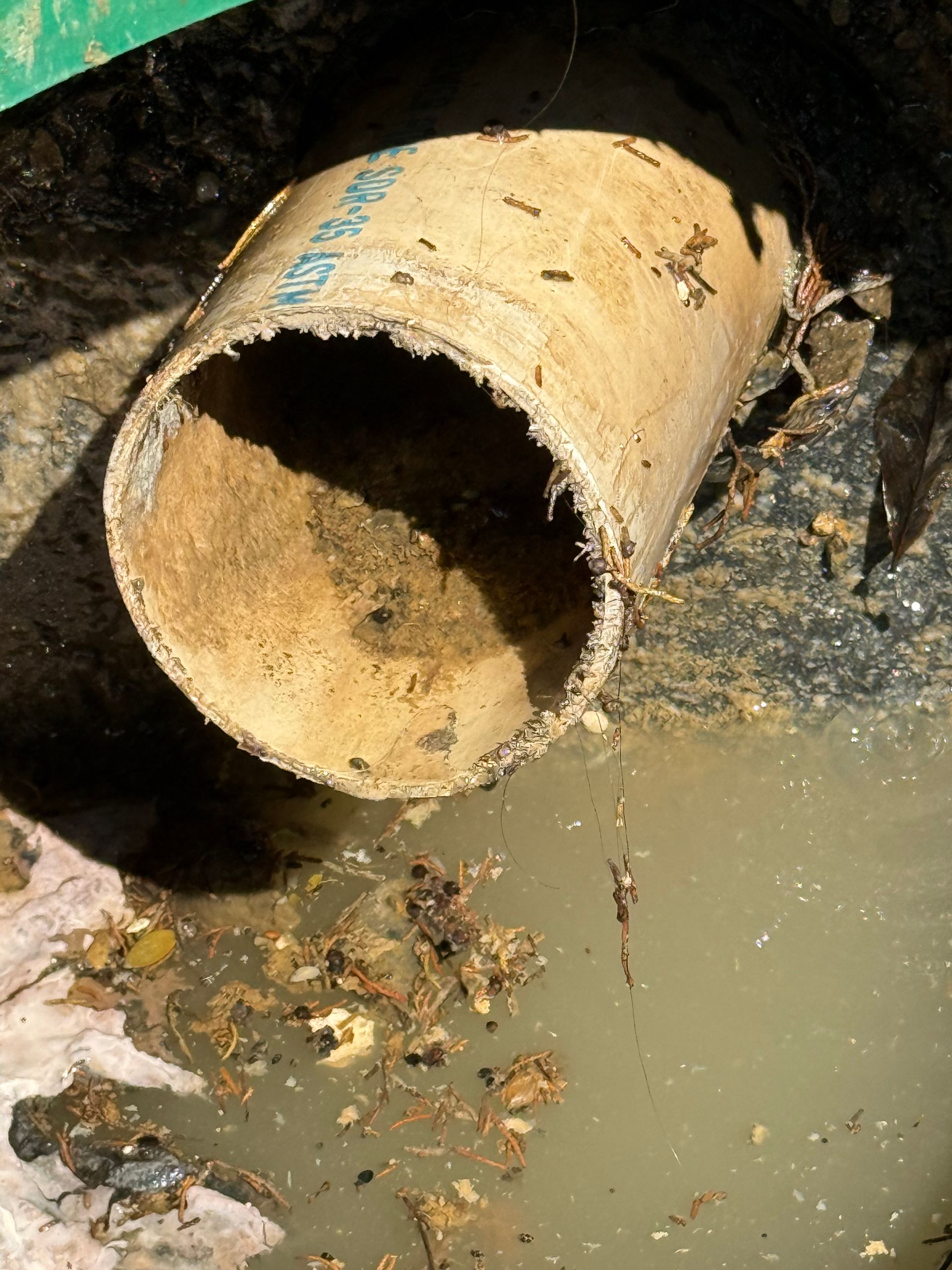Rusty pipe discharging dirty water into a muddy drain or ditch