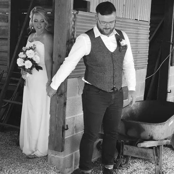 A black and white photo of a bride and groom holding hands.
