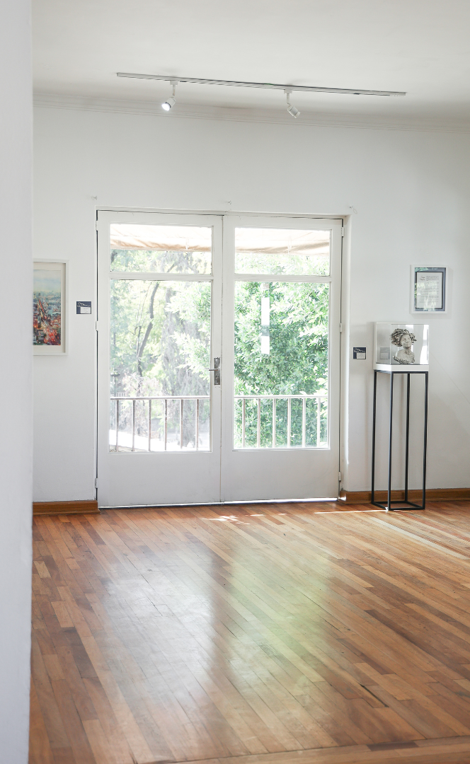 Habitación luminosa y vacía con suelos de madera, paredes blancas y puertas francesas que dan a un balcón.