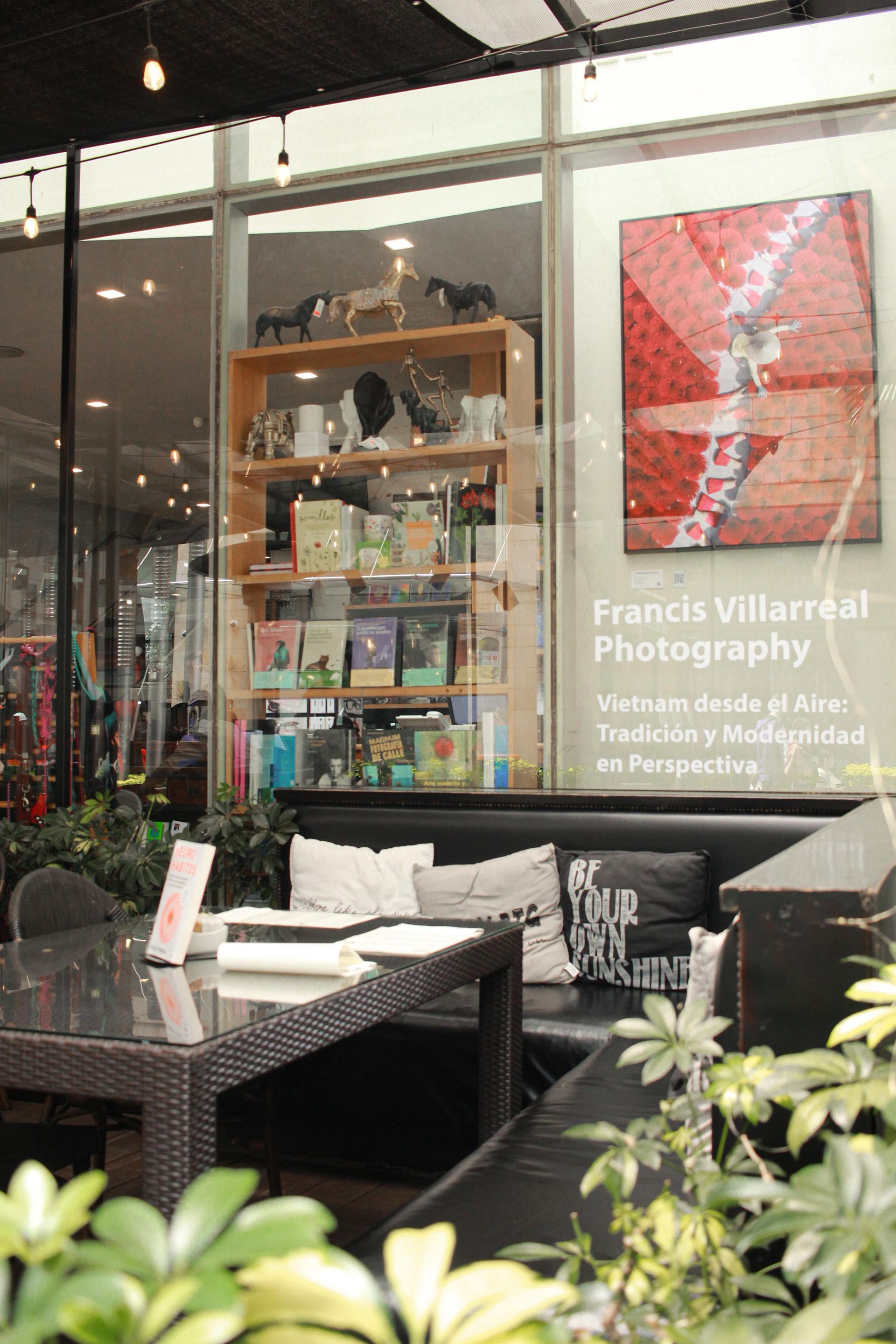 Escaparate con letrero de “Frances V Villareal Photography”, obras de arte y asientos al aire libre.