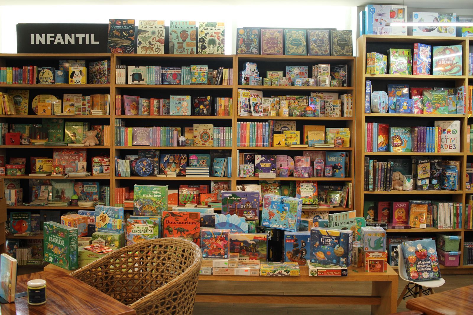 Sección infantil de la librería con coloridas estanterías y mesas de exposición de libros infantiles.
