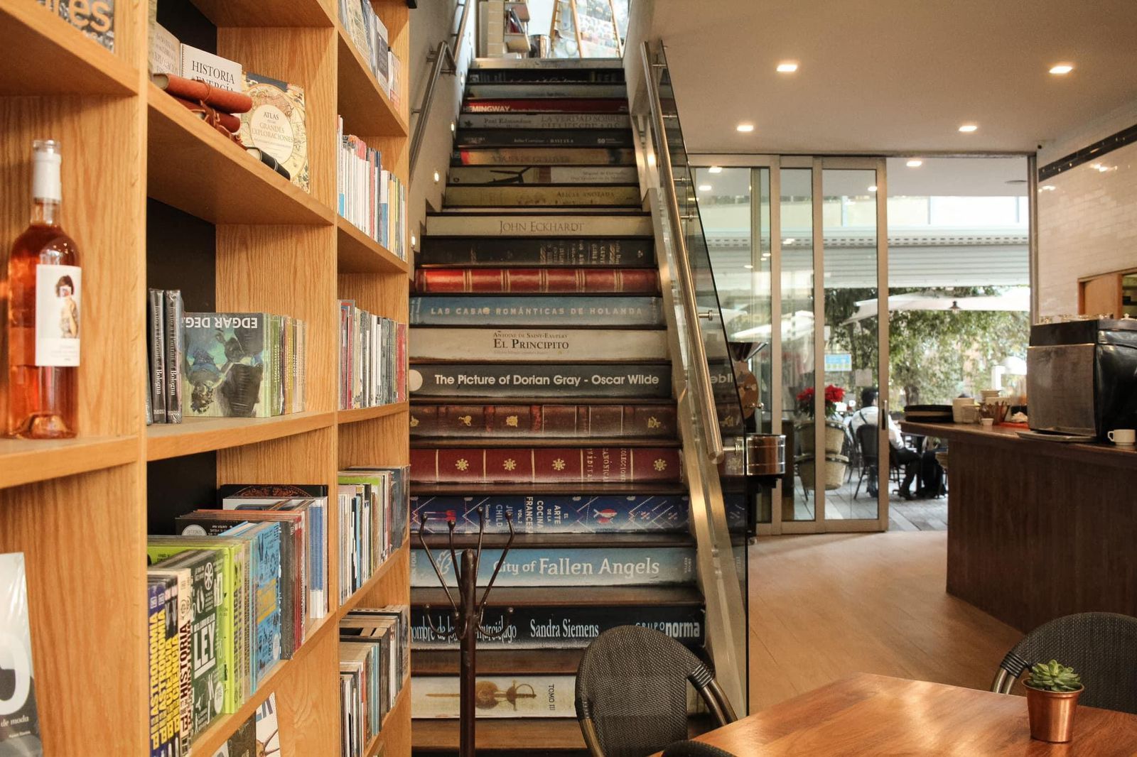 Interior acogedor de una librería con una escalera central, estanterías de madera y una iluminación cálida.