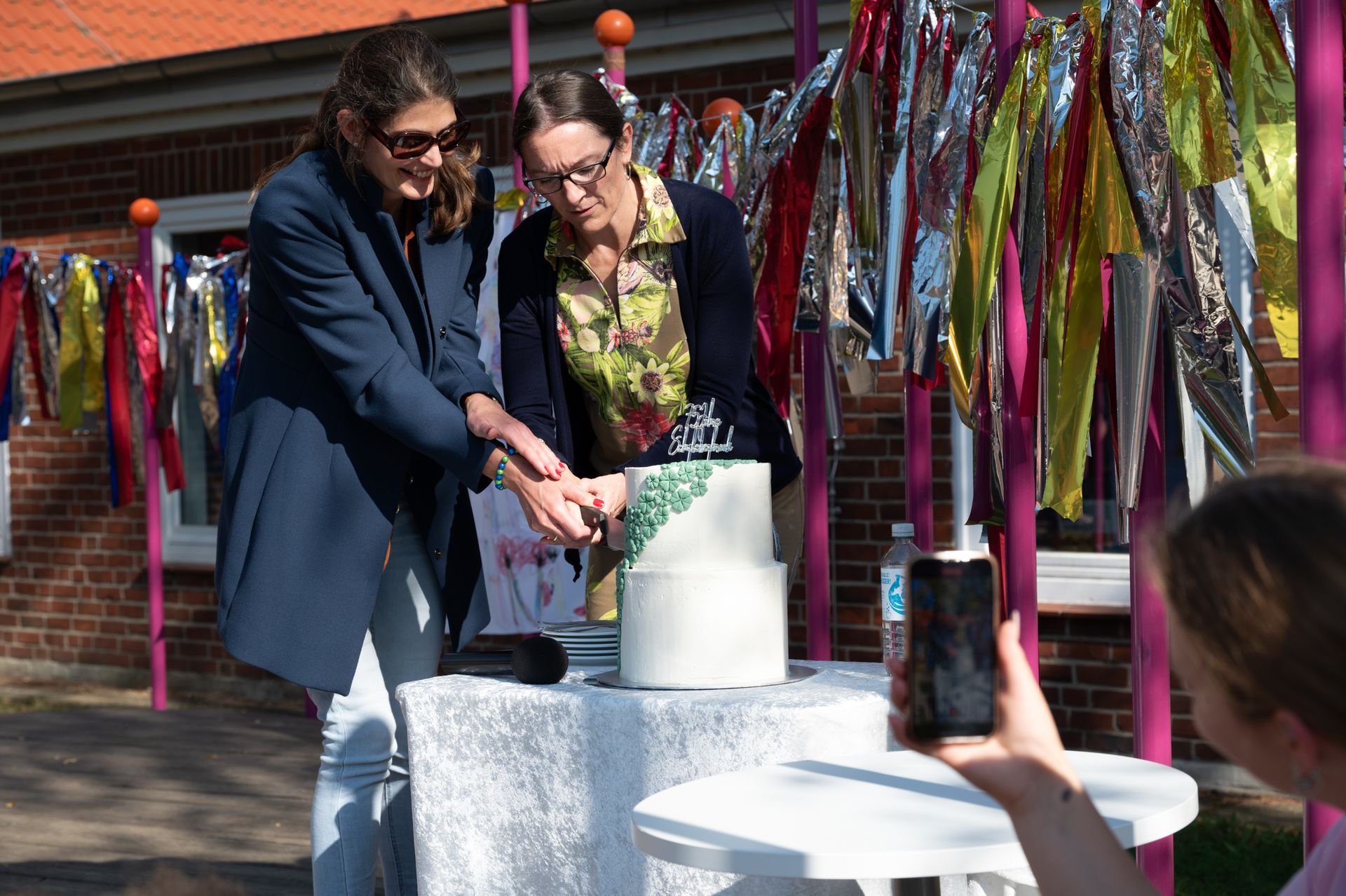 Die Hanburger Schulsenatorin Ksenija Bekeris und die Schulleiterin der Schule Iserbrook, Tanja Blumhardt, schneiden die Geburtstagstorte zum 75. Schuljubiläum an.