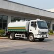 White tanker truck with green stripes parked outside a building.