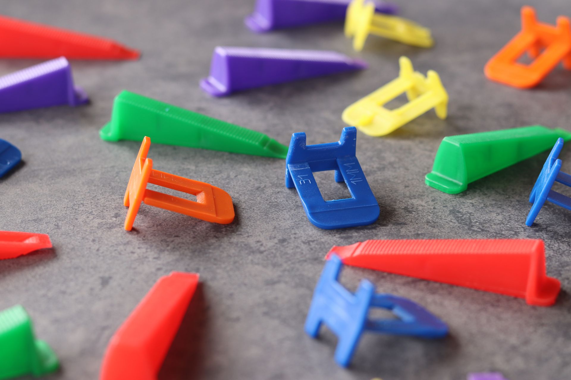 Colorful plastic clothespins scattered on gray fabric background.