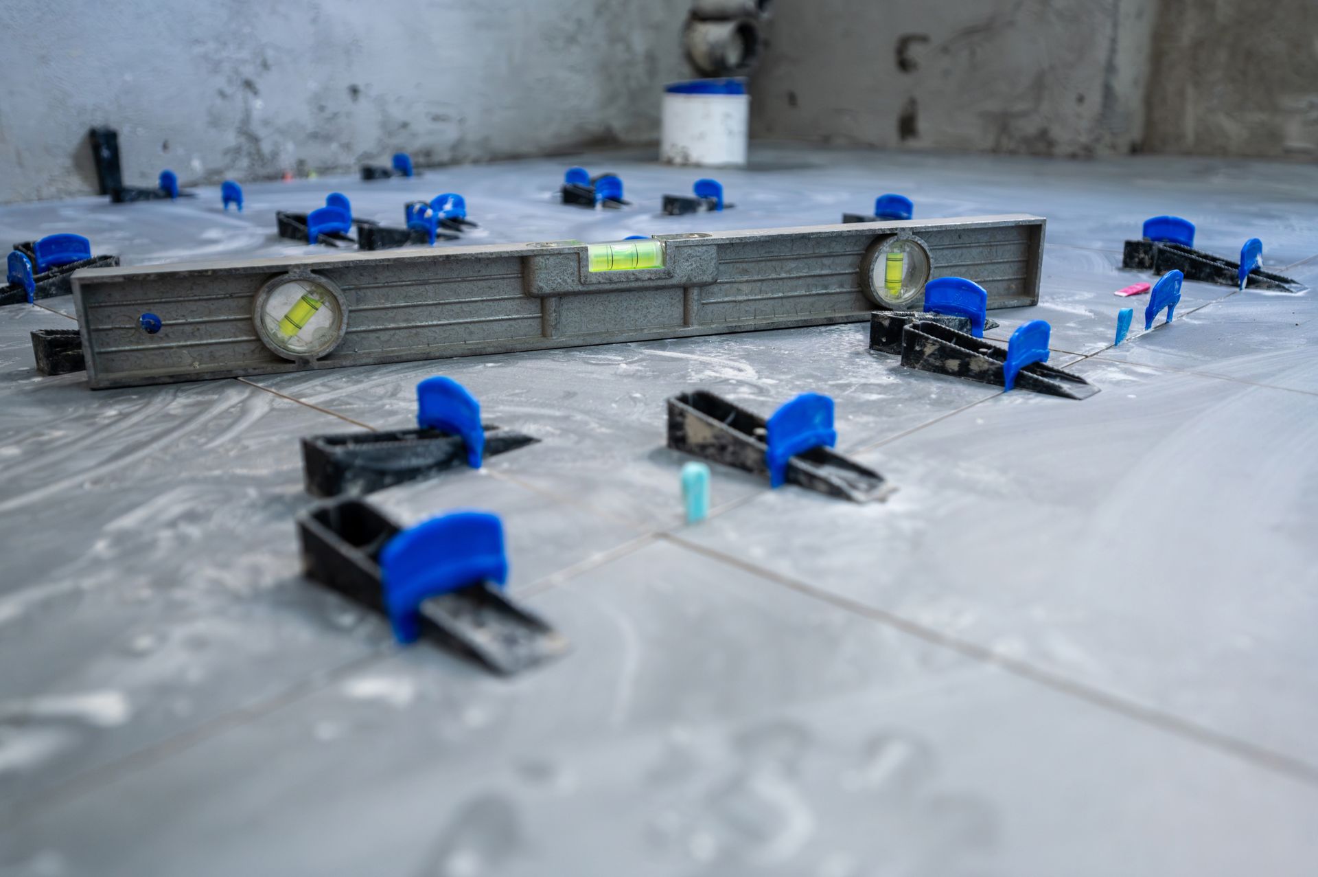 Blue clamps holding metal parts on a protective sheet in a workshop setting