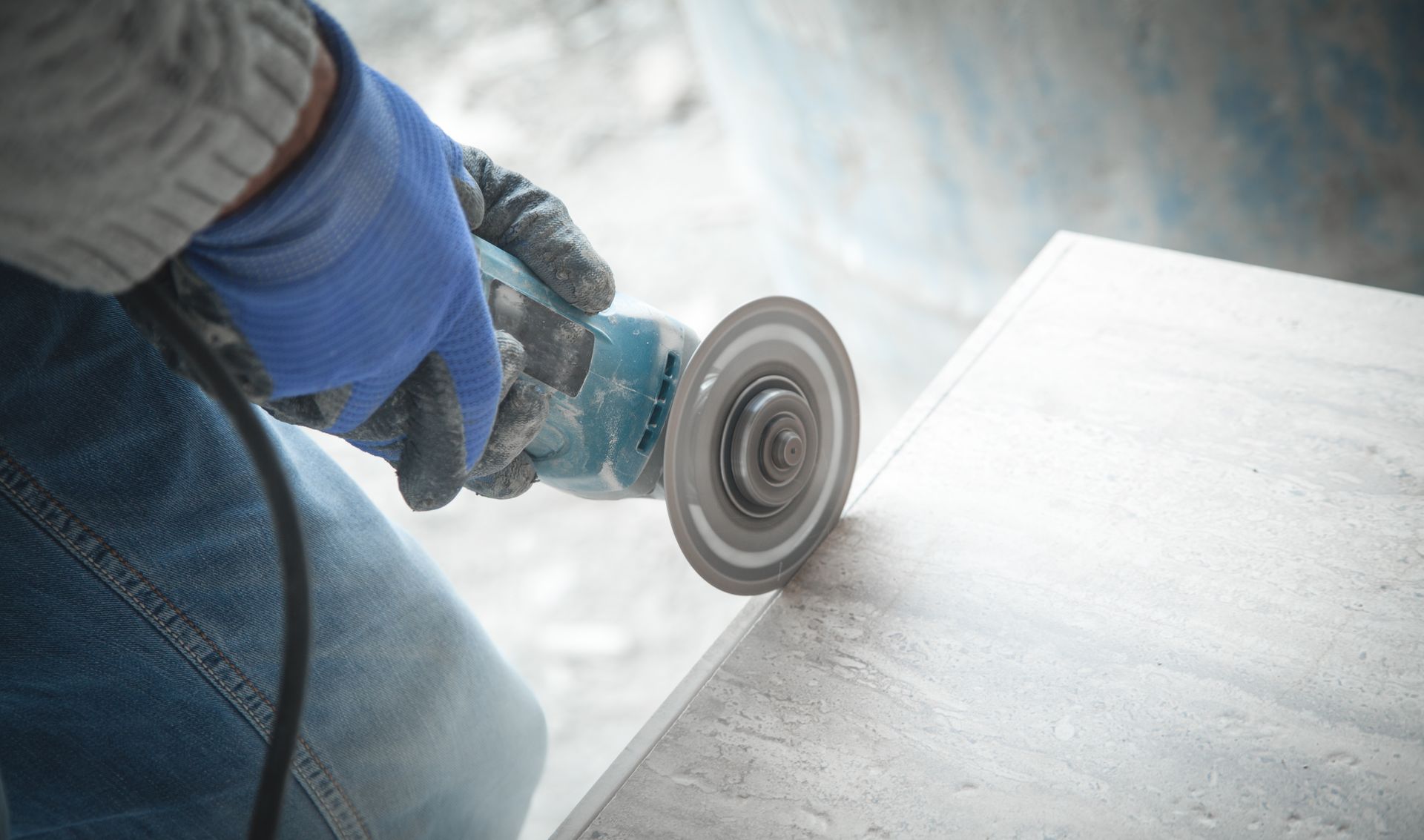 Person using an angle grinder to cut a metal sheet, with sparks and dust in a workshop setting