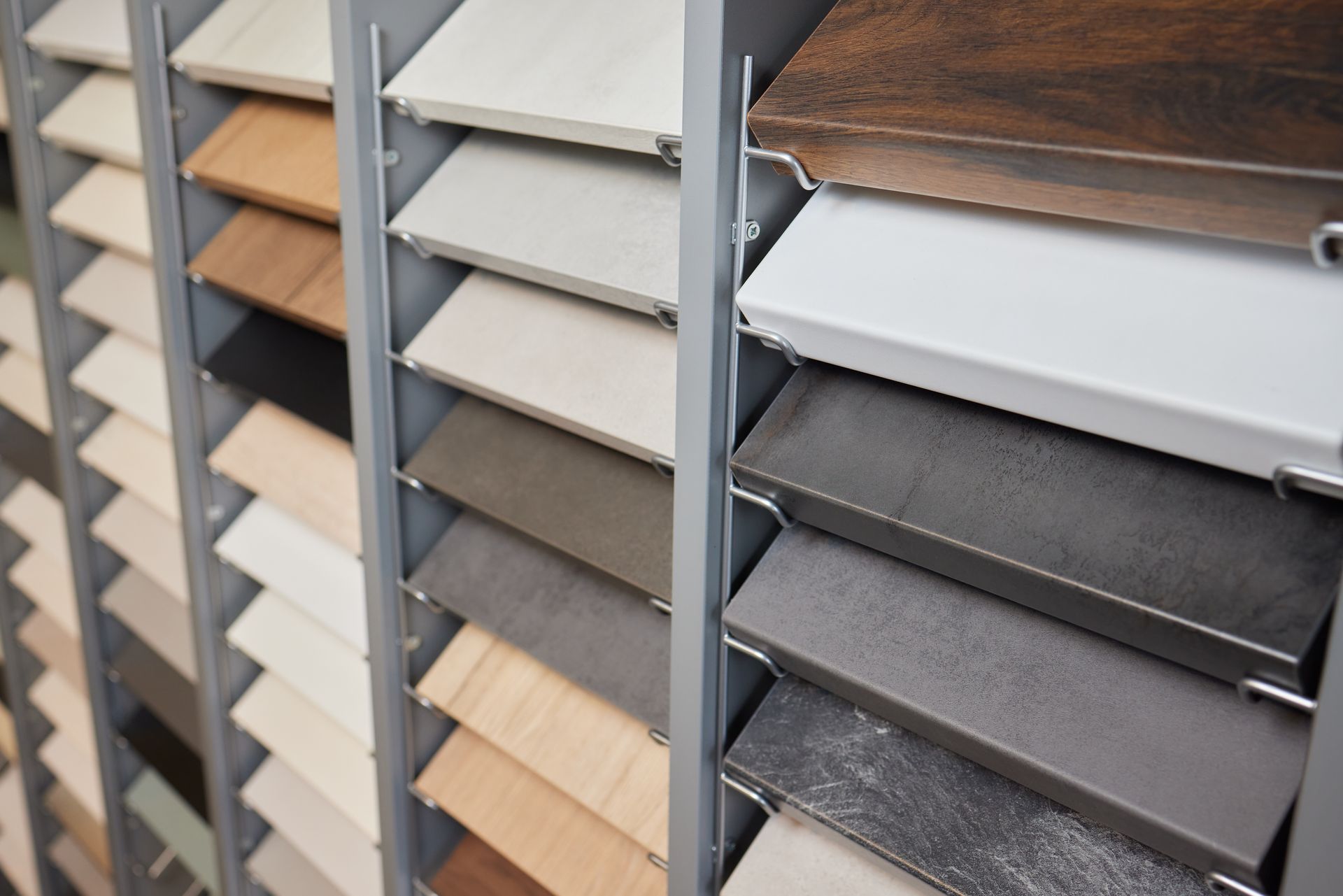 Rows of laminate flooring samples in a showroom, arranged by color and wood finish.