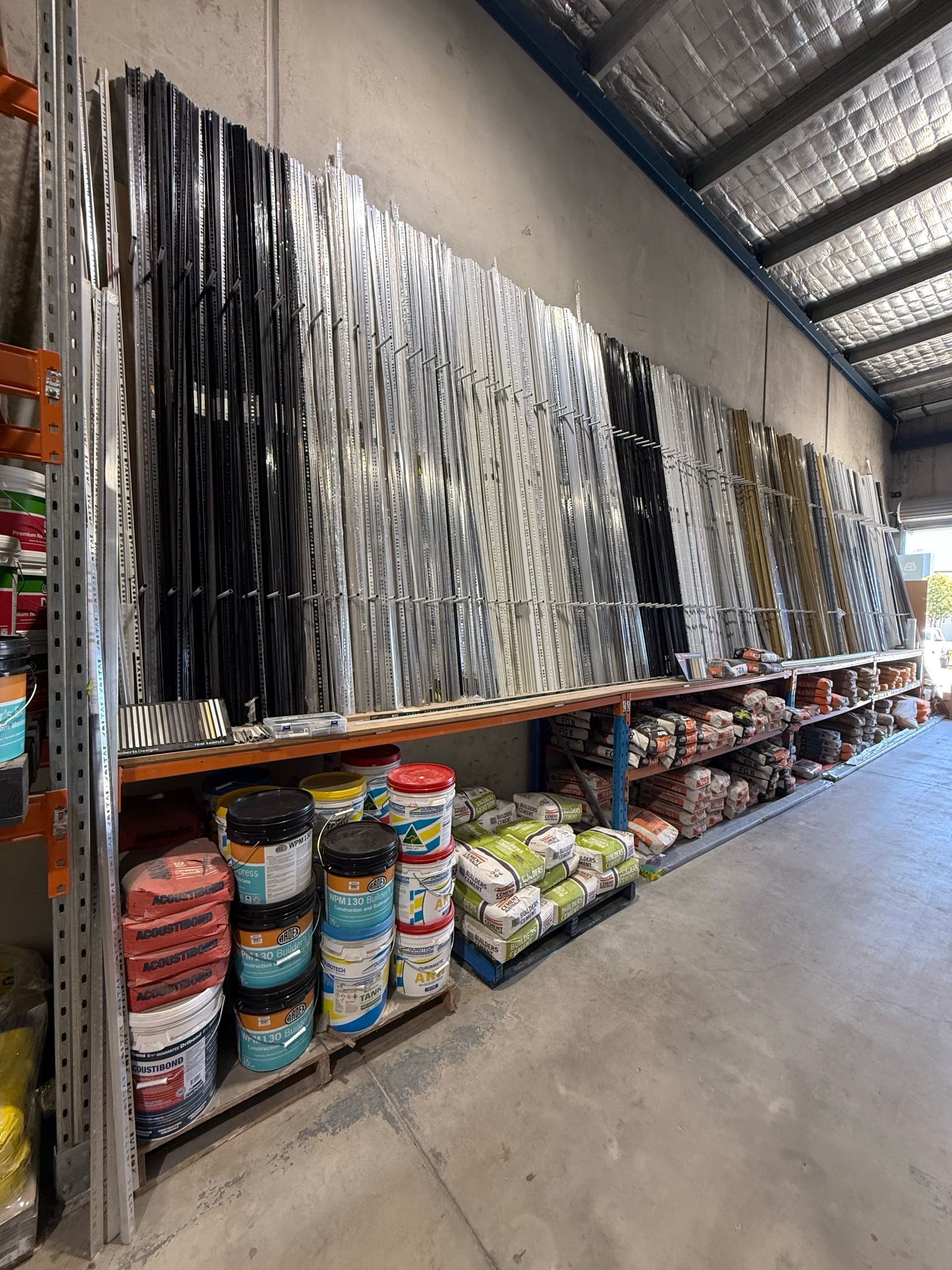Metal shelving with stacked rolls of fabric or tarp in a warehouse aisle