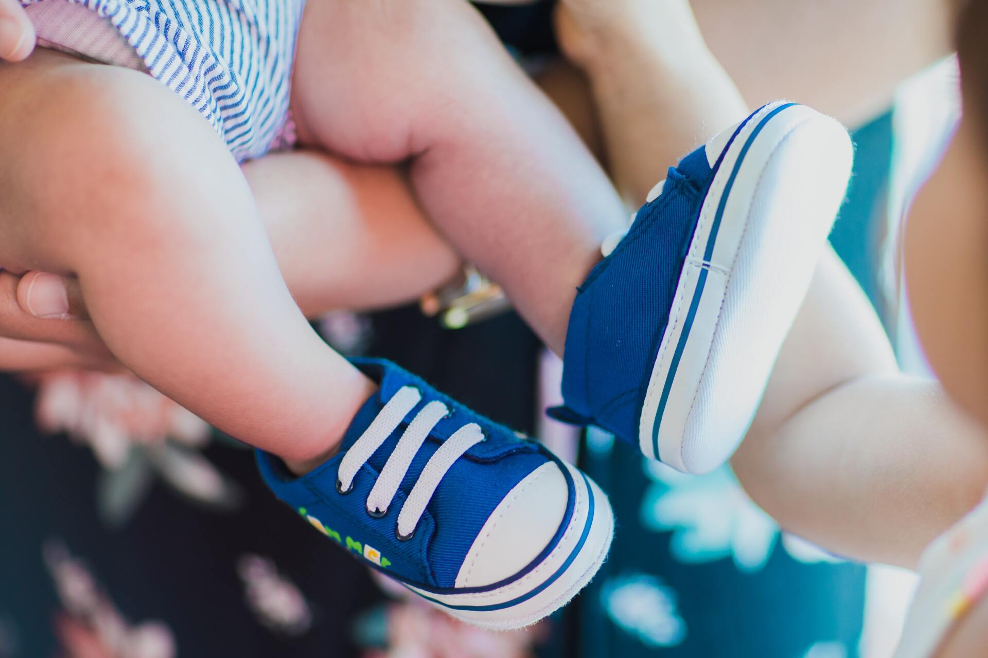 A woman is holding a baby wearing blue shoes.