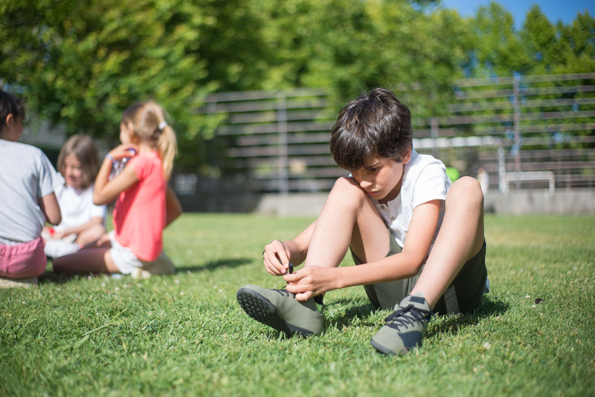 Child Tying Shoes While Sitting in Grass