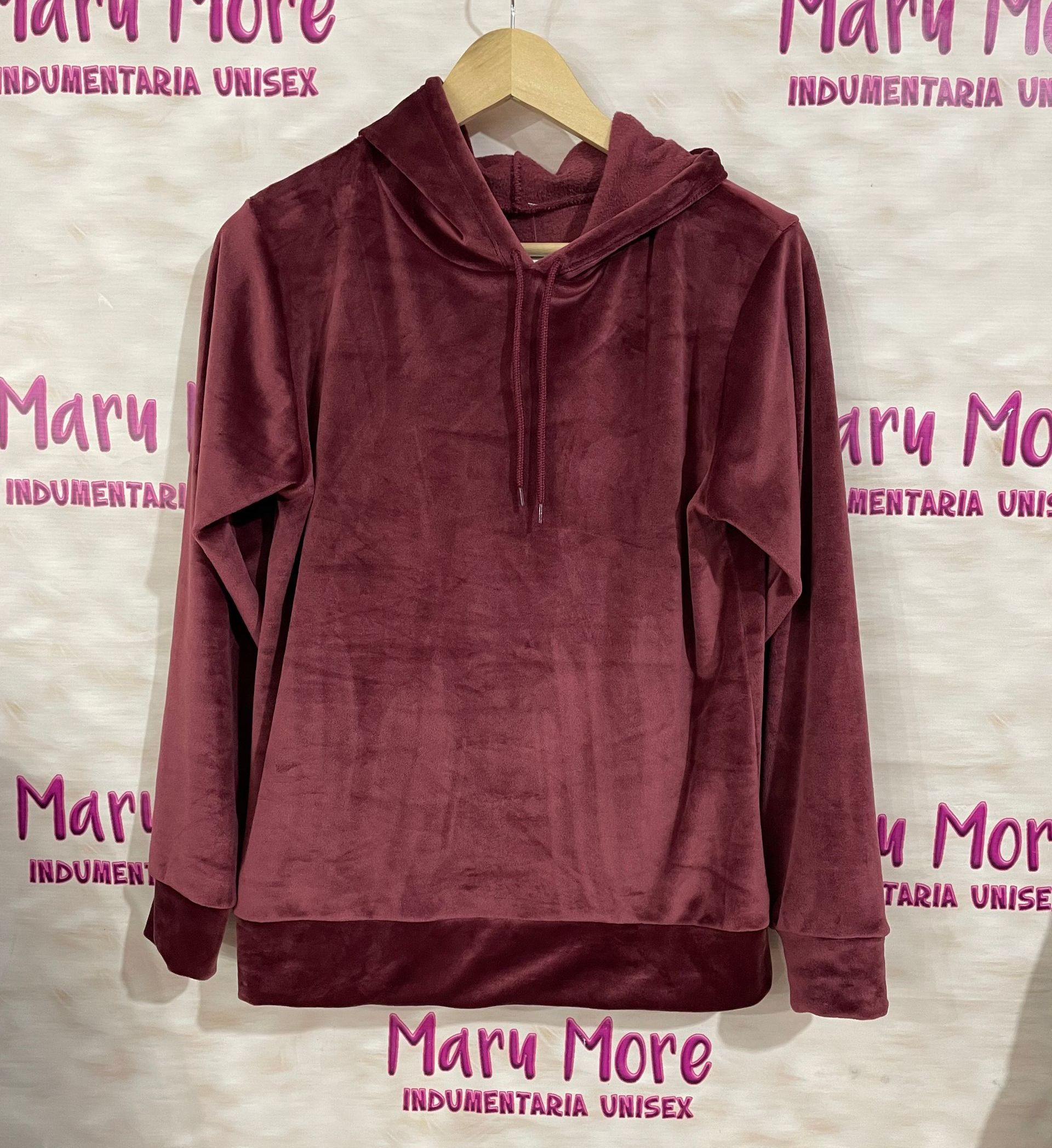 Una sudadera con capucha color granate está colgada en una percha frente a una pared que dice Mary More.
