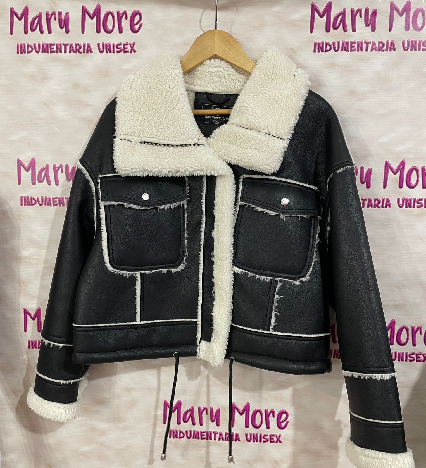 Una chaqueta negra con cuello blanco está colgada en una percha
