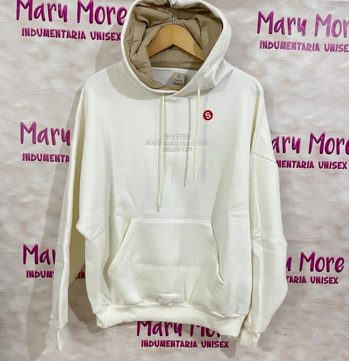 Una sudadera blanca de Mary More está colgada en una percha.