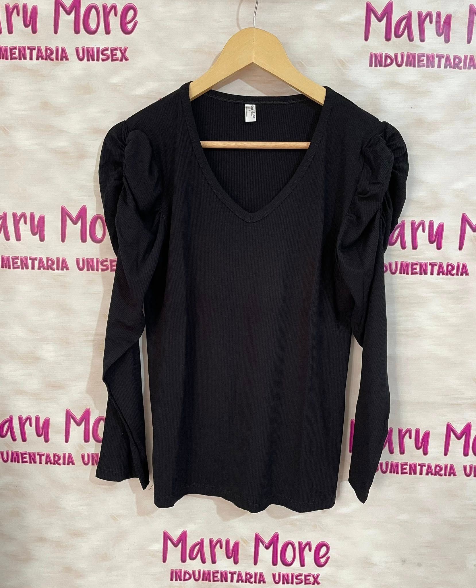 Una camisa negra con mangas con volantes cuelga de una percha.