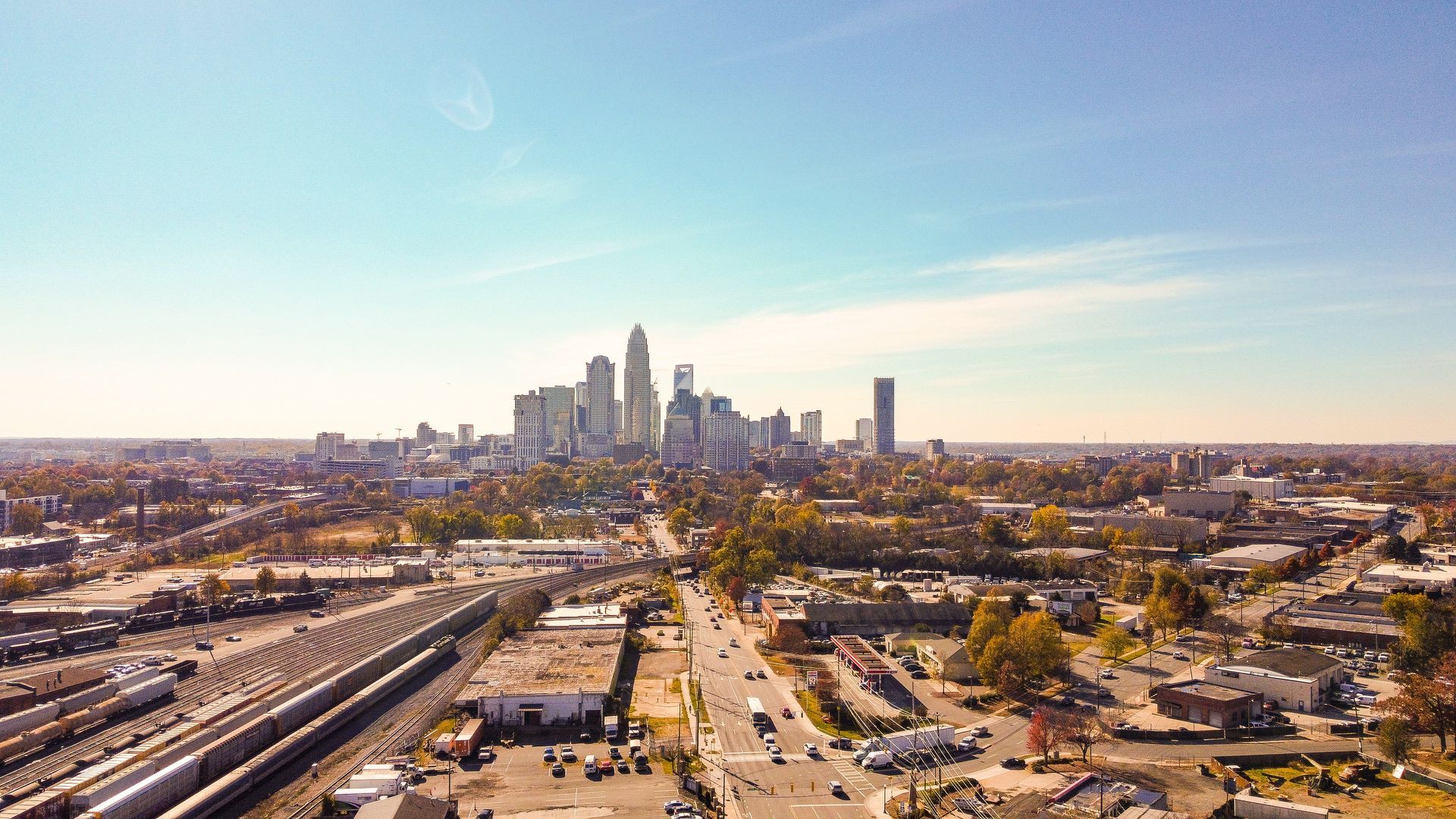 Aerial view of a city skyline under a clear blue sky, with roads and buildings in the foreground