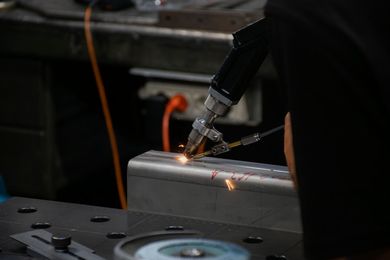 Testa di saldatura laser in azione su lamiera d'acciaio