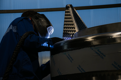 Saldatore con maschera che lavora con torcia TIG su profilo in acciaio inox