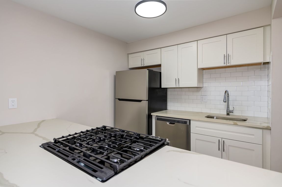 A kitchen with a stove top oven and a refrigerator