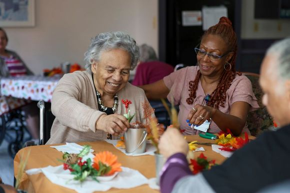 Caregiver assisting smiling elderly woman with daily care at Brookside Commons Farmington Hills