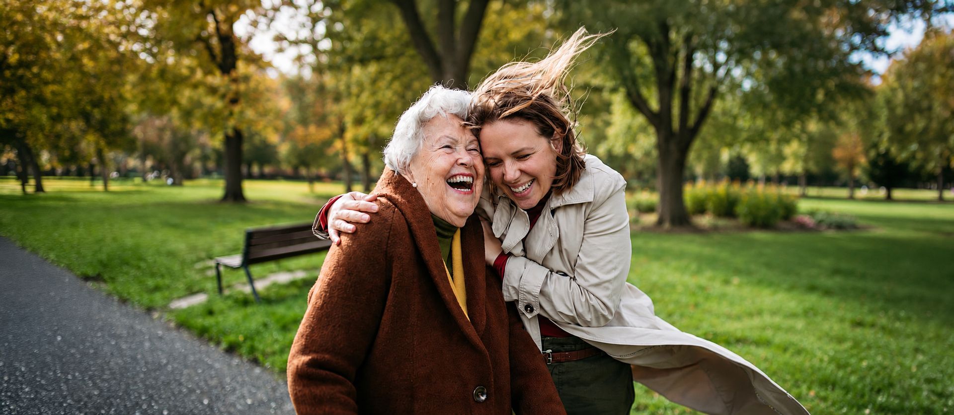 Two people laughing and hugging in a green park on a sunny day