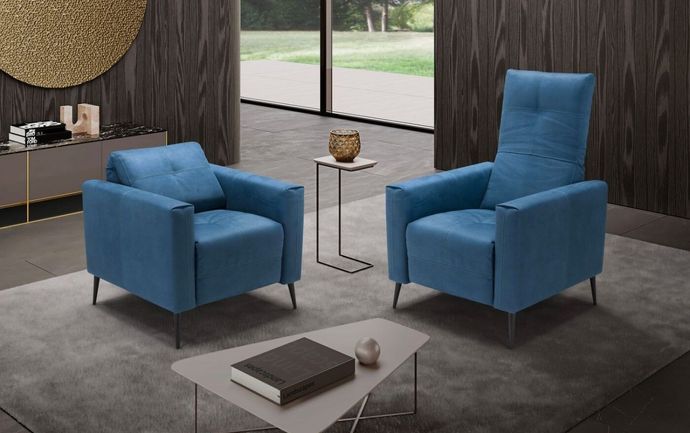 Soggiorno moderno con poltrona a fantasia, pouf marrone e parete rivestita in legno rustico.