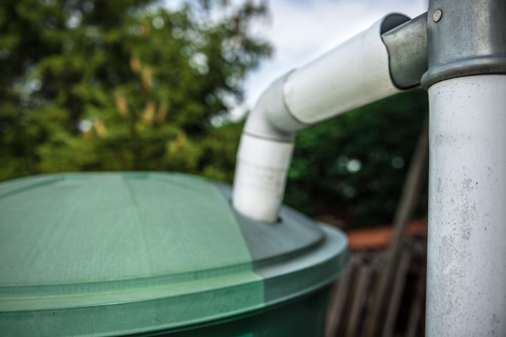 A Close Up Of A Rain Barrel With A Pipe Attached To It — BAS Plumbing & Drainage In Forresters Beach, NSW