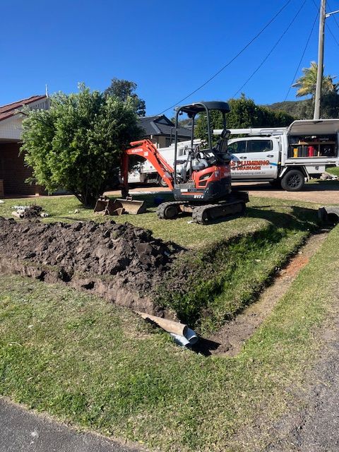 A Bobcat Digging Holes To Fix Blocked Drains — BAS Plumbing & Drainage In Forresters Beach, NSW