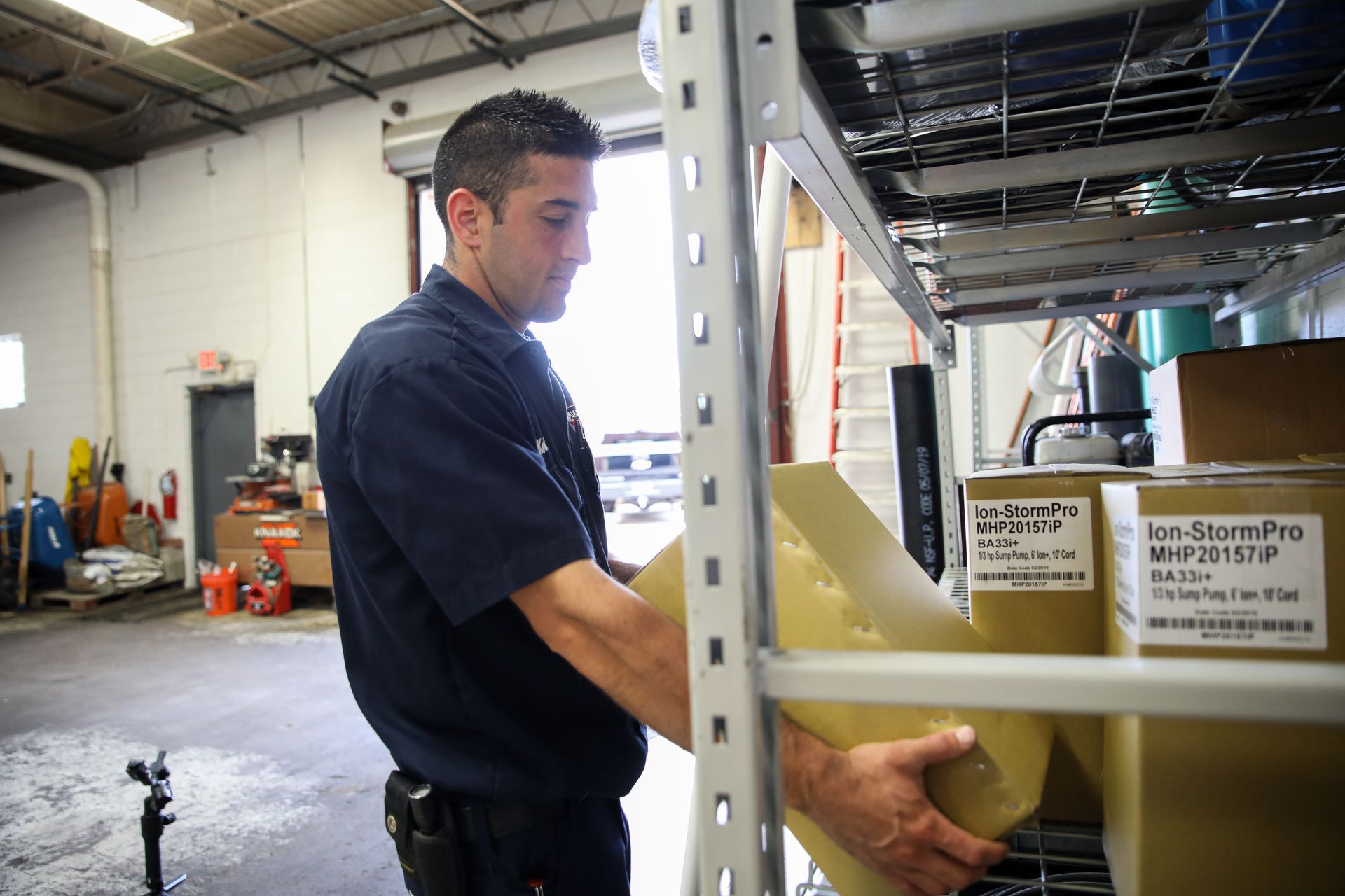 A man is working in a plumbing warehouse with boxes on shelves.
