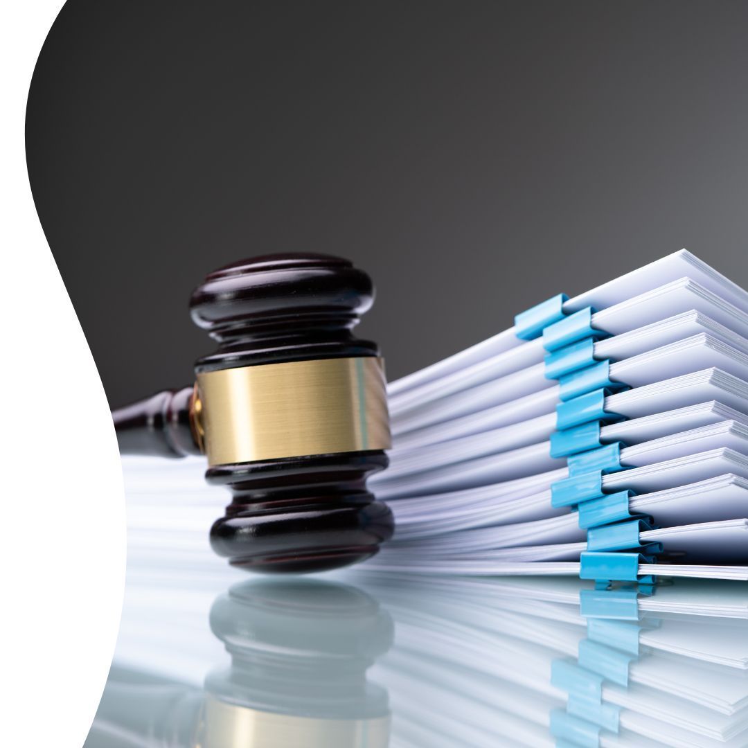 Judge’s gavel beside a stack of documents bound with blue clips on a reflective surface