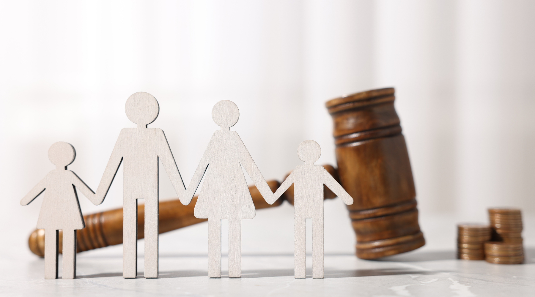 Paper family figures beside a judge's gavel and coins, symbolizing divorce or legal finance matters