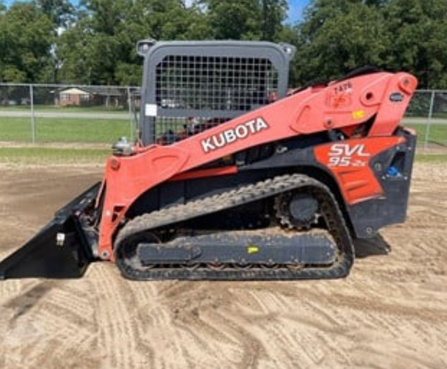 A kubota skid steer is parked in a dirt field.