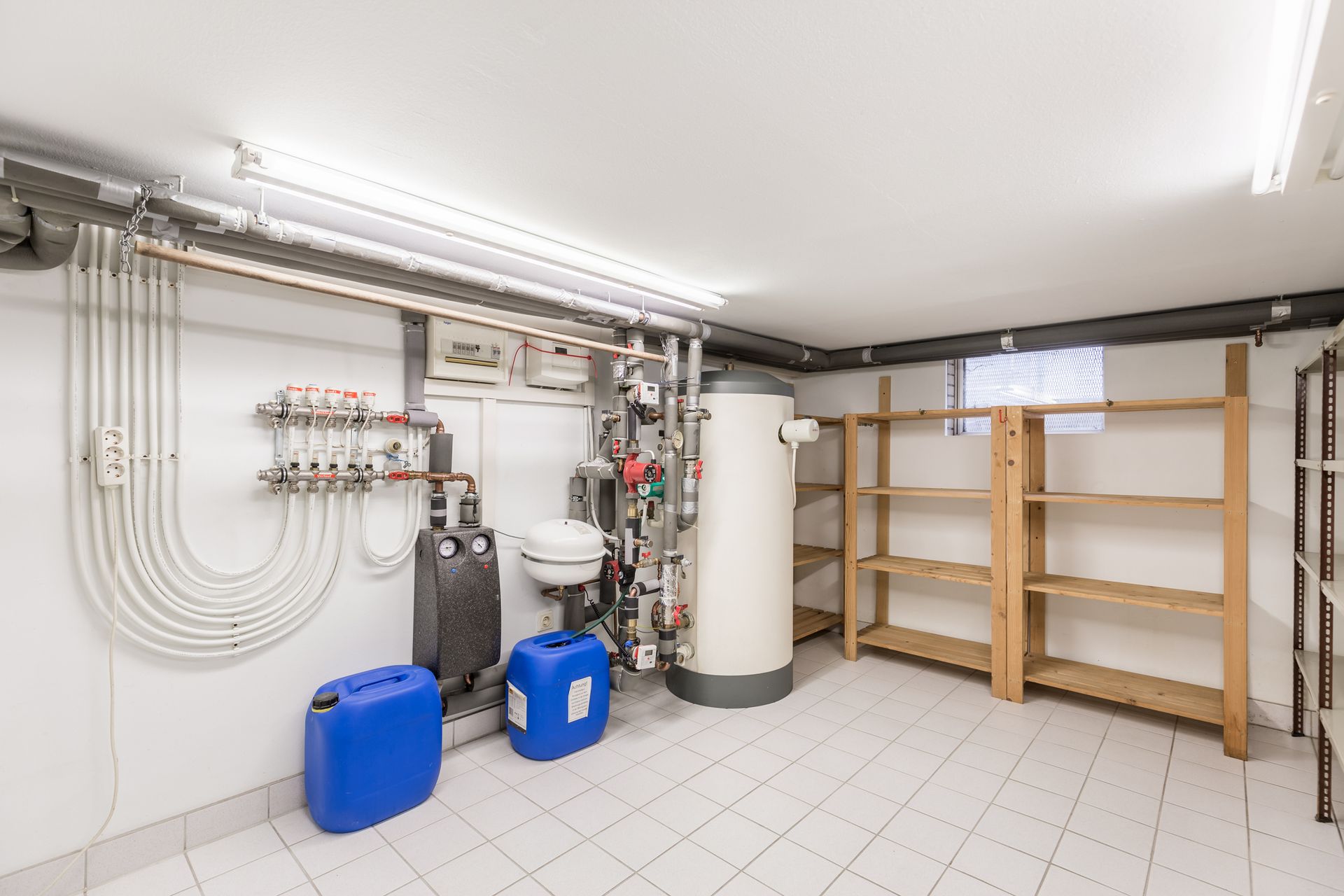A basement with a water heater , sink , and shelves.