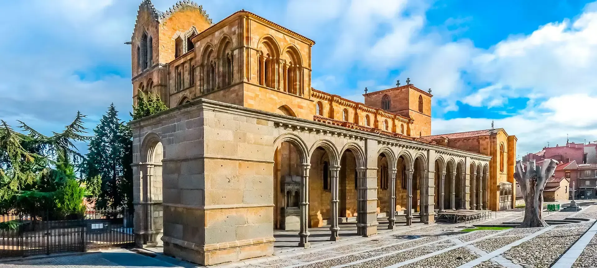 Catedral histórica de piedra con arcos y campanario bajo un cielo azul brillante.