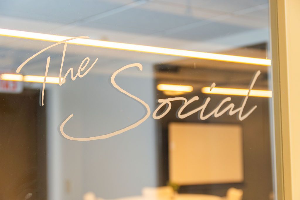 Neon sign reading “The Social” on a glass storefront door