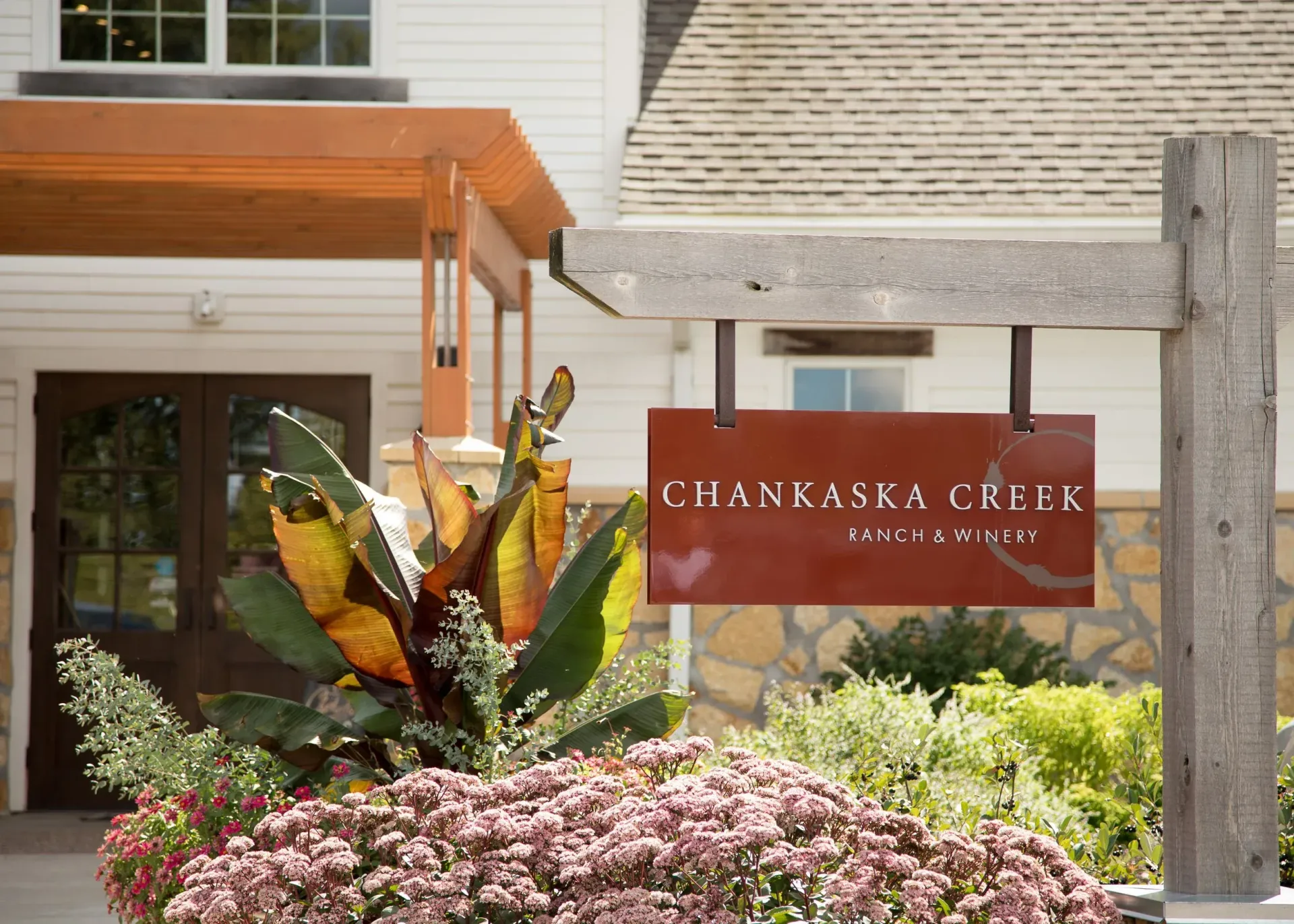 Chaminade Creek sign by a building entrance, surrounded by tropical plants and flowers