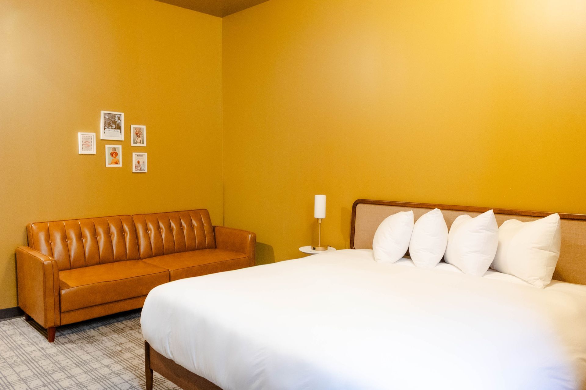 Minimal bedroom with mustard walls, white bed, and tan sofa