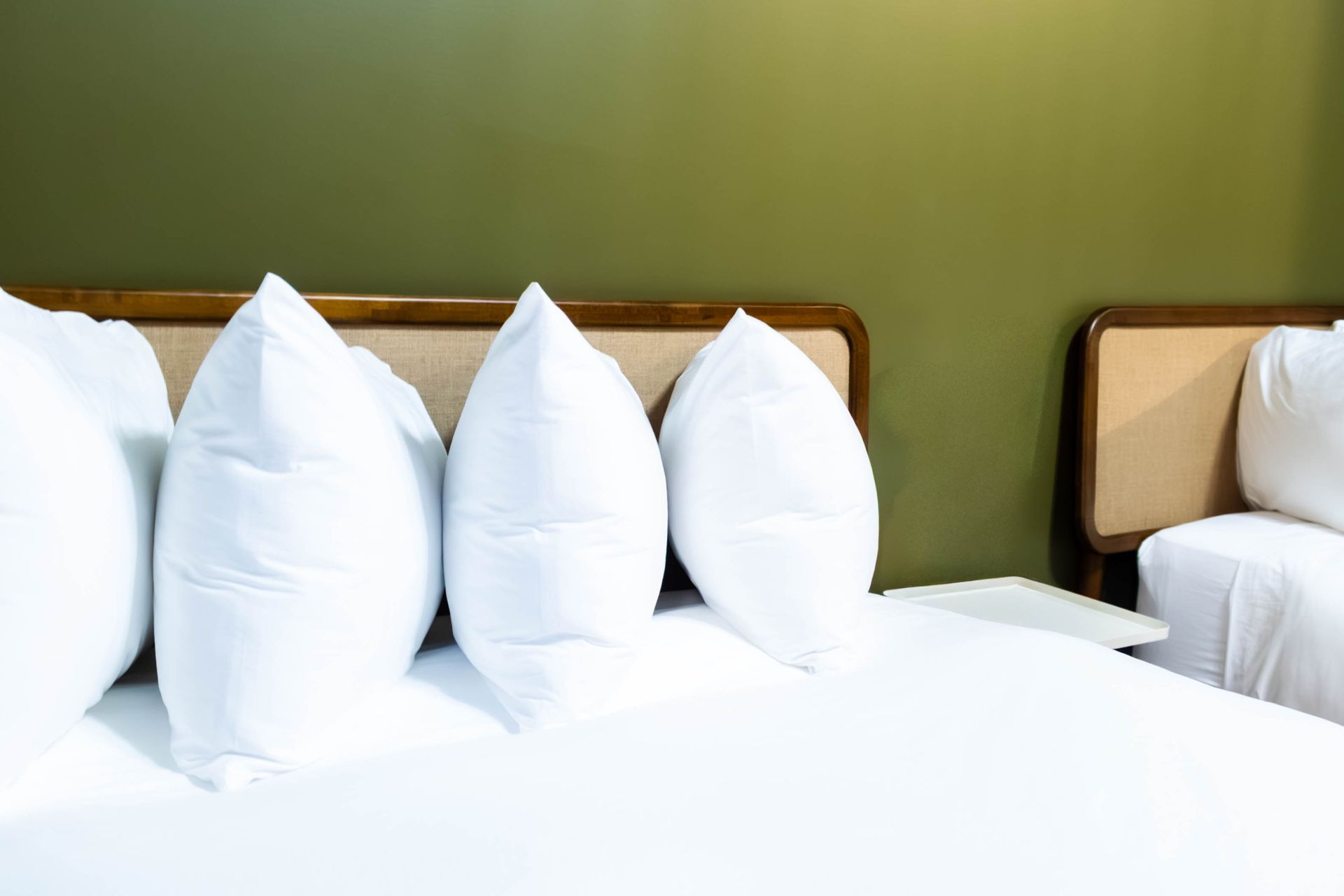White pillows on a neatly made bed in a simple green-walled bedroom