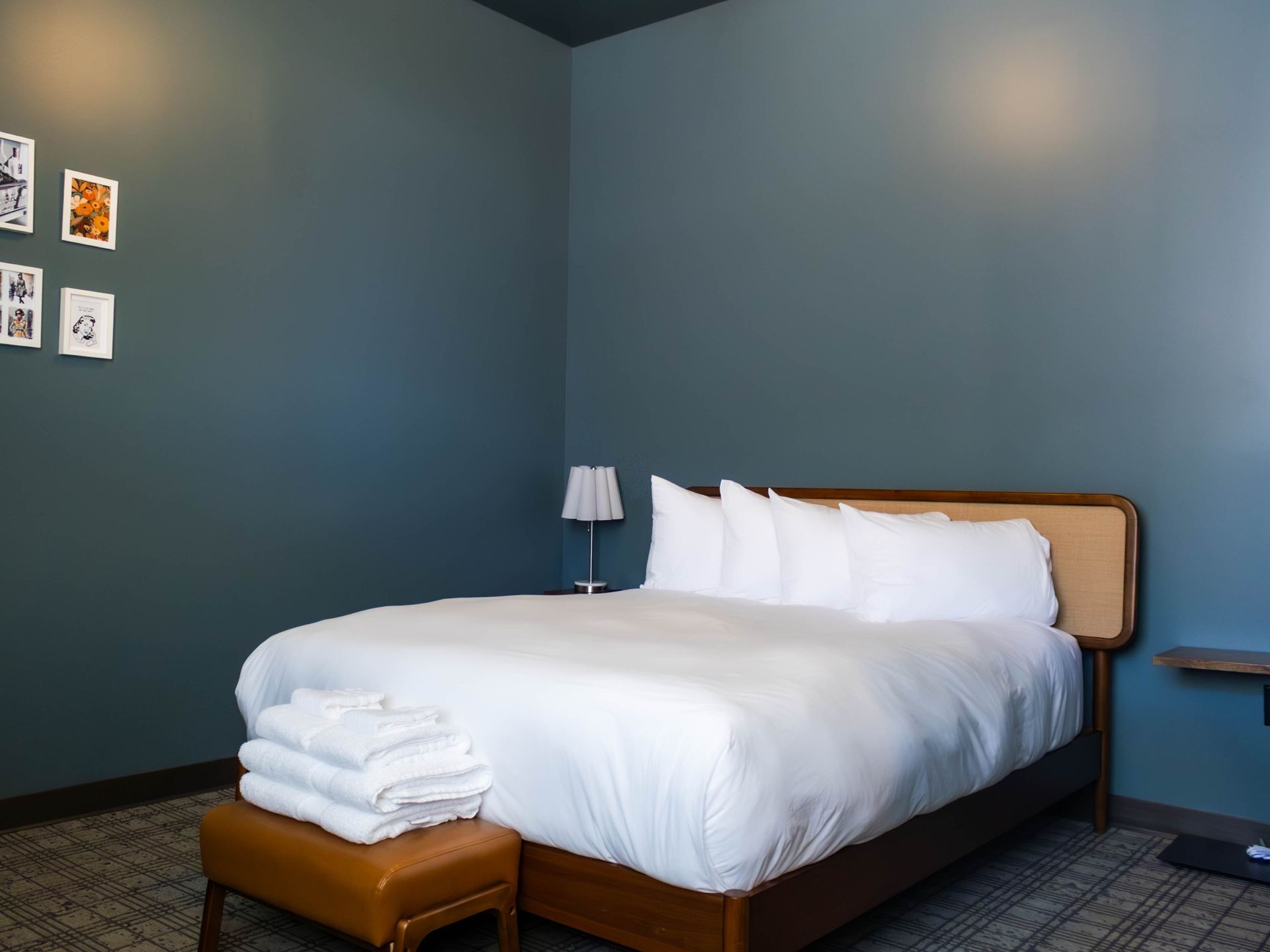 Minimal bedroom with a white bed, teal walls, and a small lamp on the nightstand.