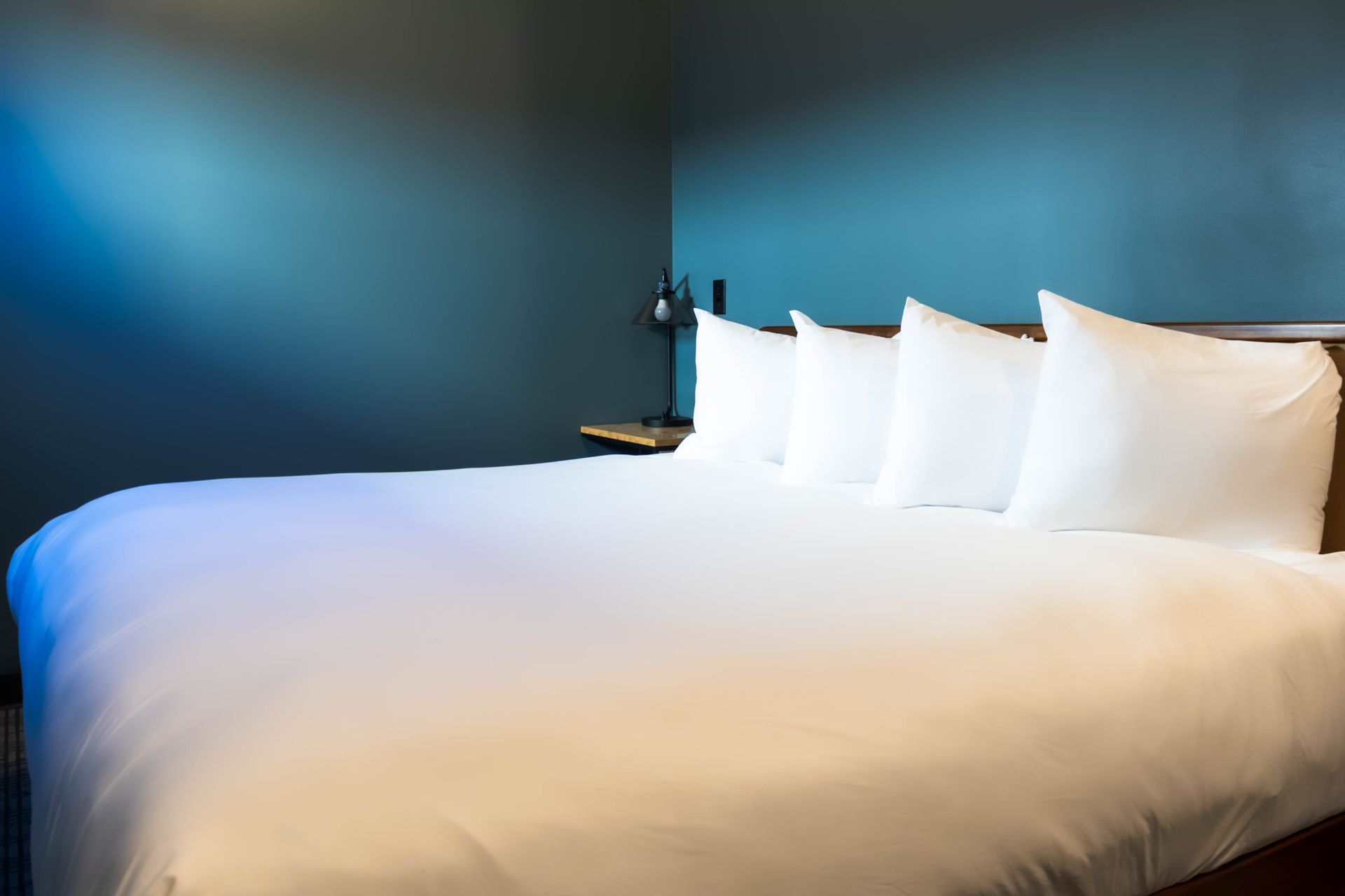 White bed with pillows in a modern blue-walled bedroom
