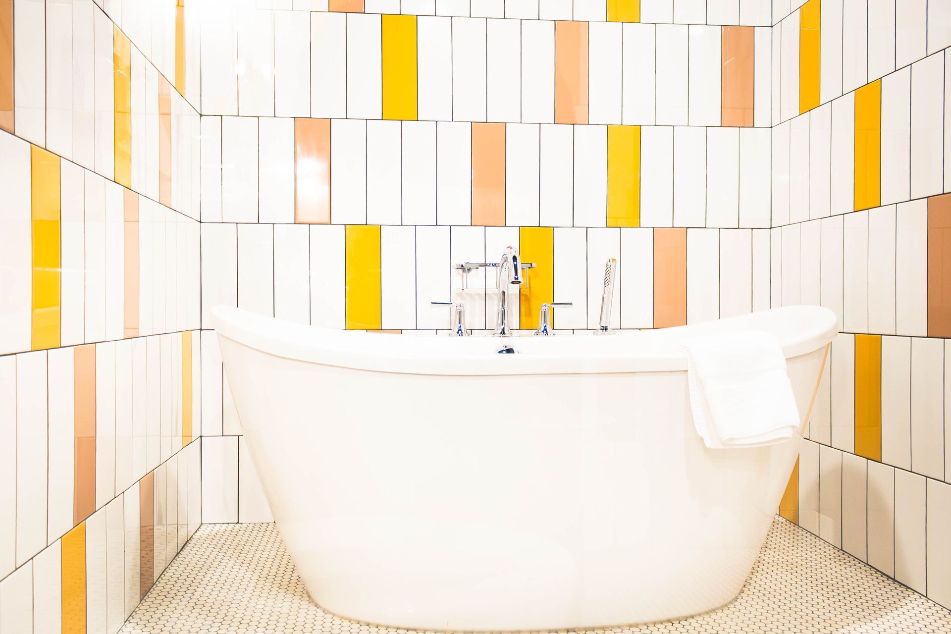 Modern bathroom with a white tub, chrome faucet, and white-and-yellow tiled walls