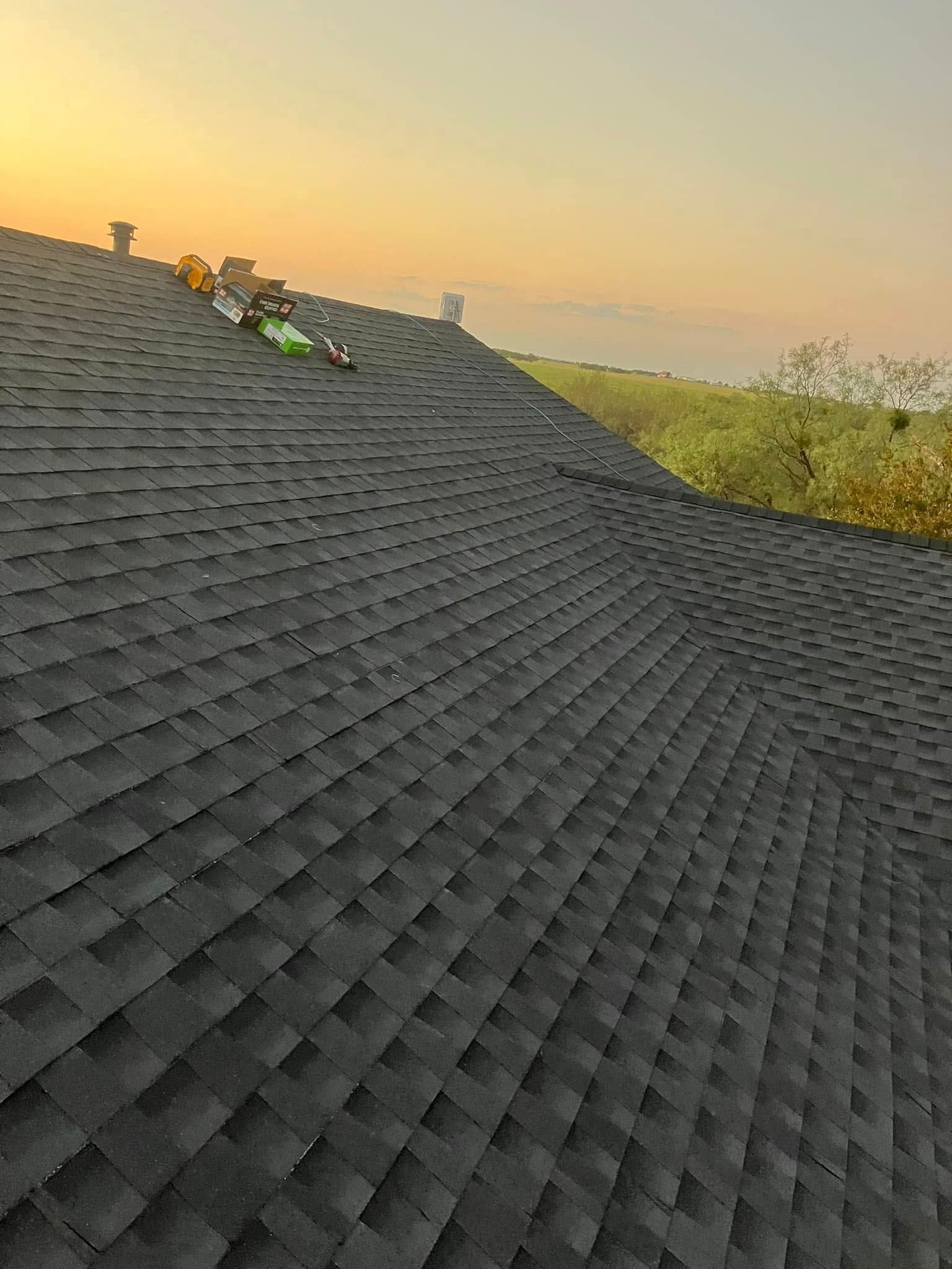 A close up of a roof with a sunset in the background.