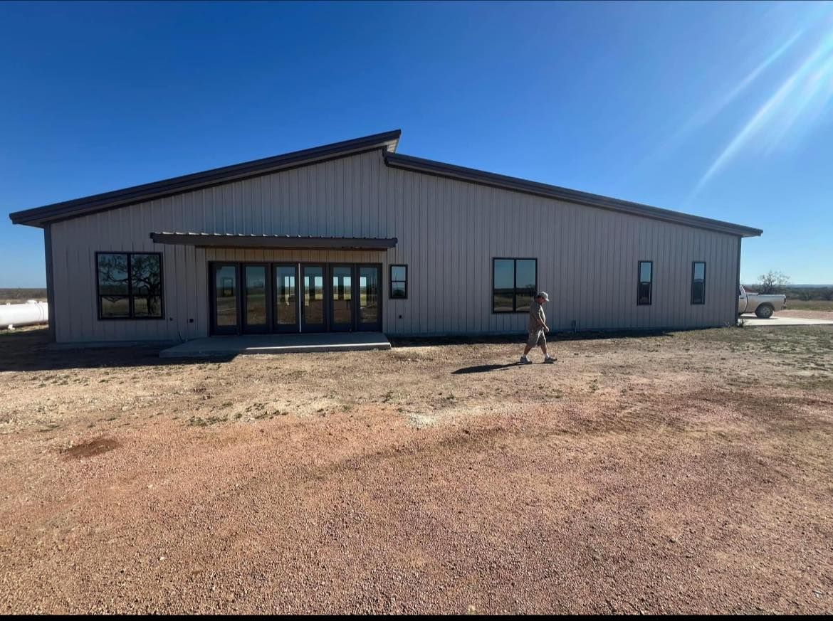 A large building with a lot of windows is sitting on top of a dirt field.