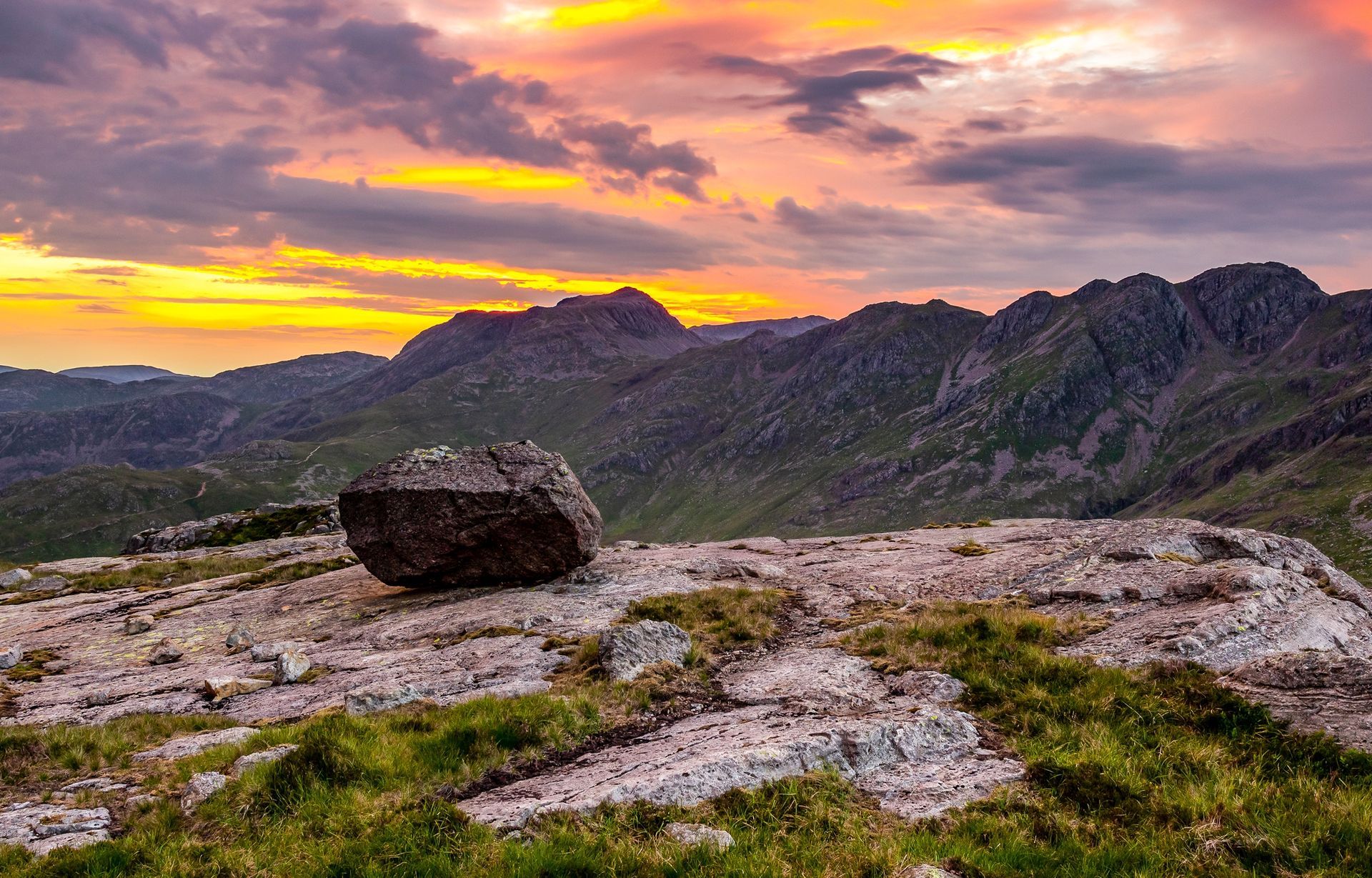 A large rock on top of a mountain at sunset