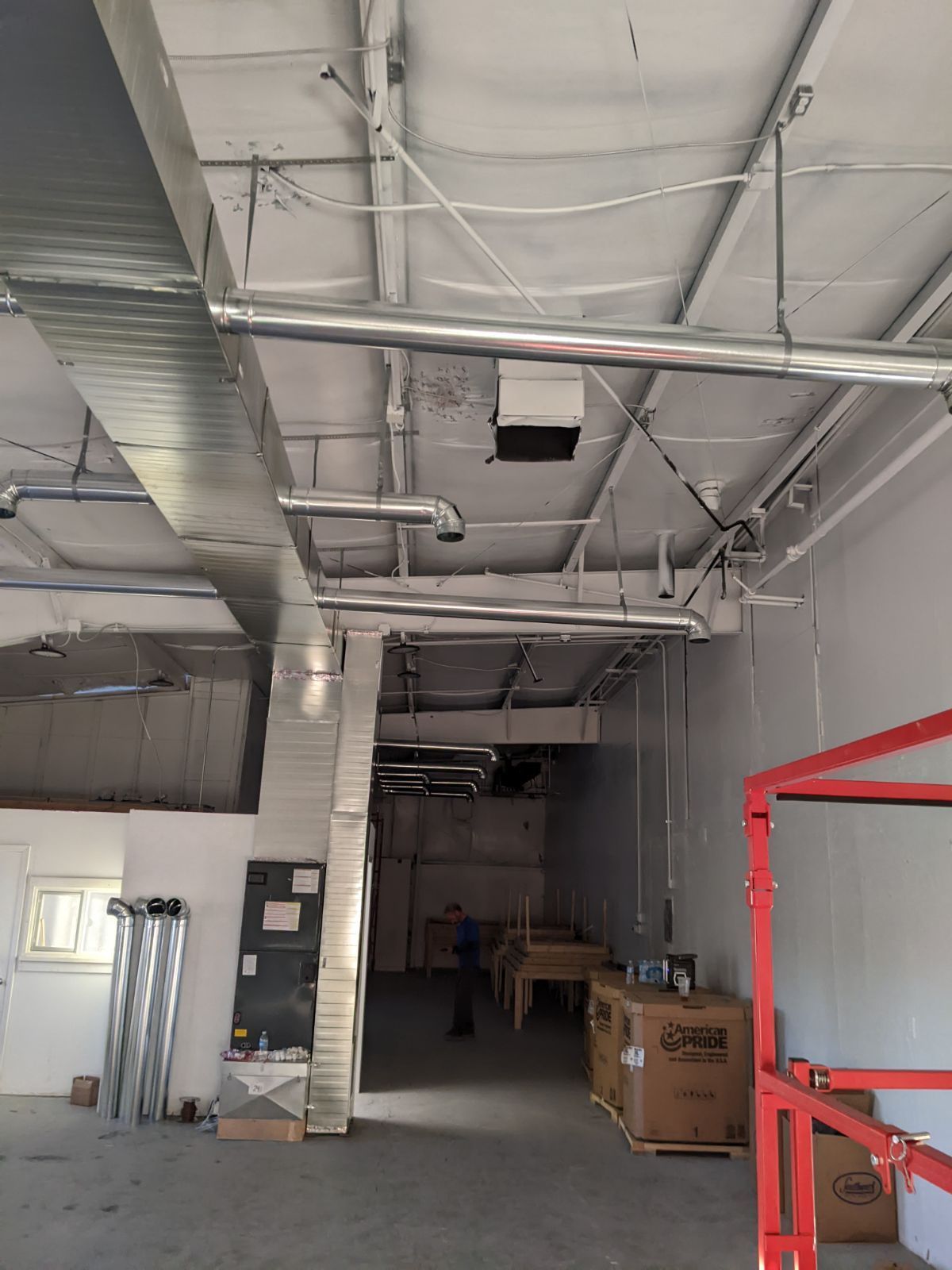 Interior of a commercial space with ductwork and exposed ceiling.  A person stands in the background.