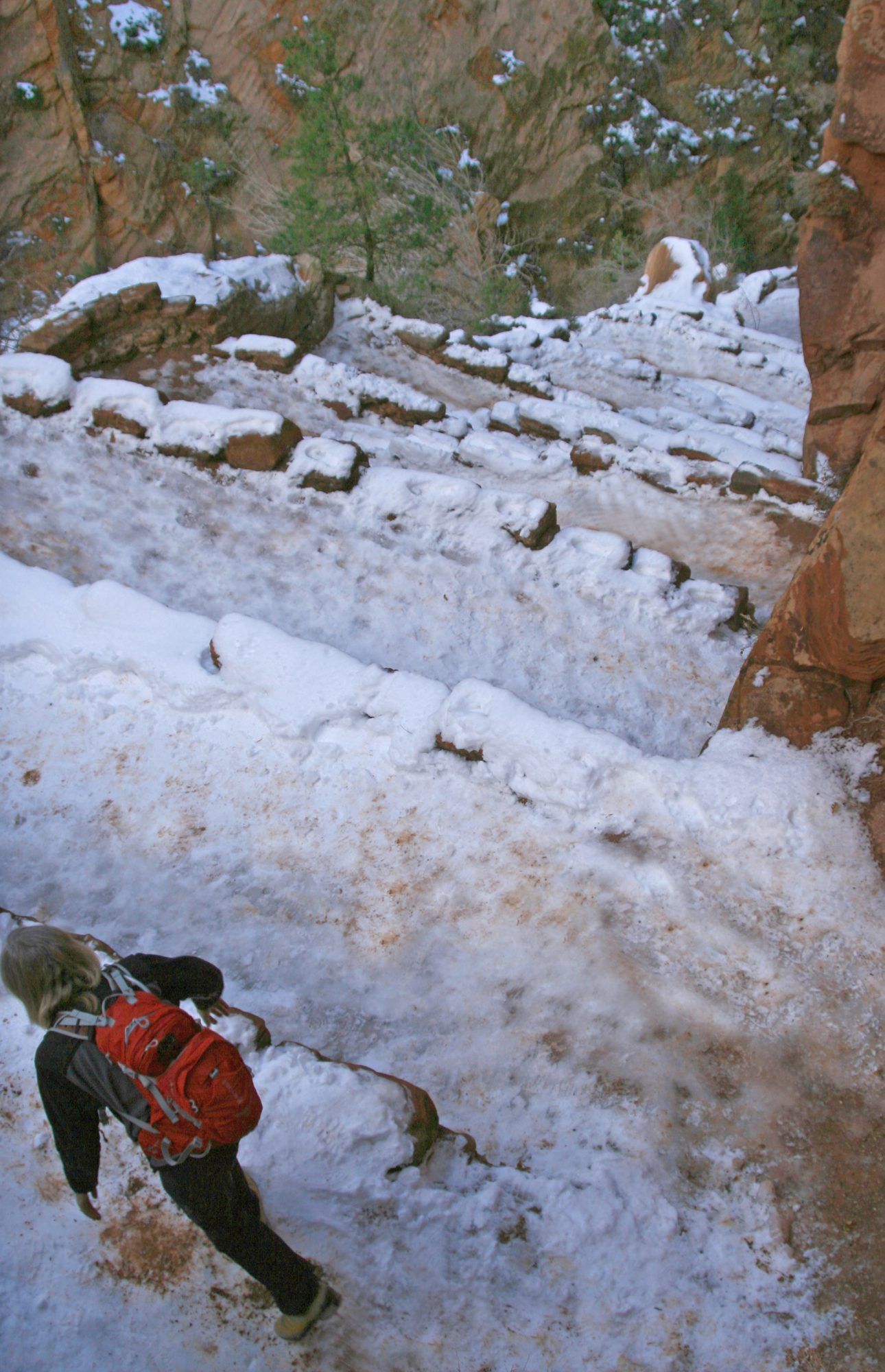 A hiker climbs a snowy Walter’s Wiggles, the switchbacks on the West Rim Trail to Angels Landing.