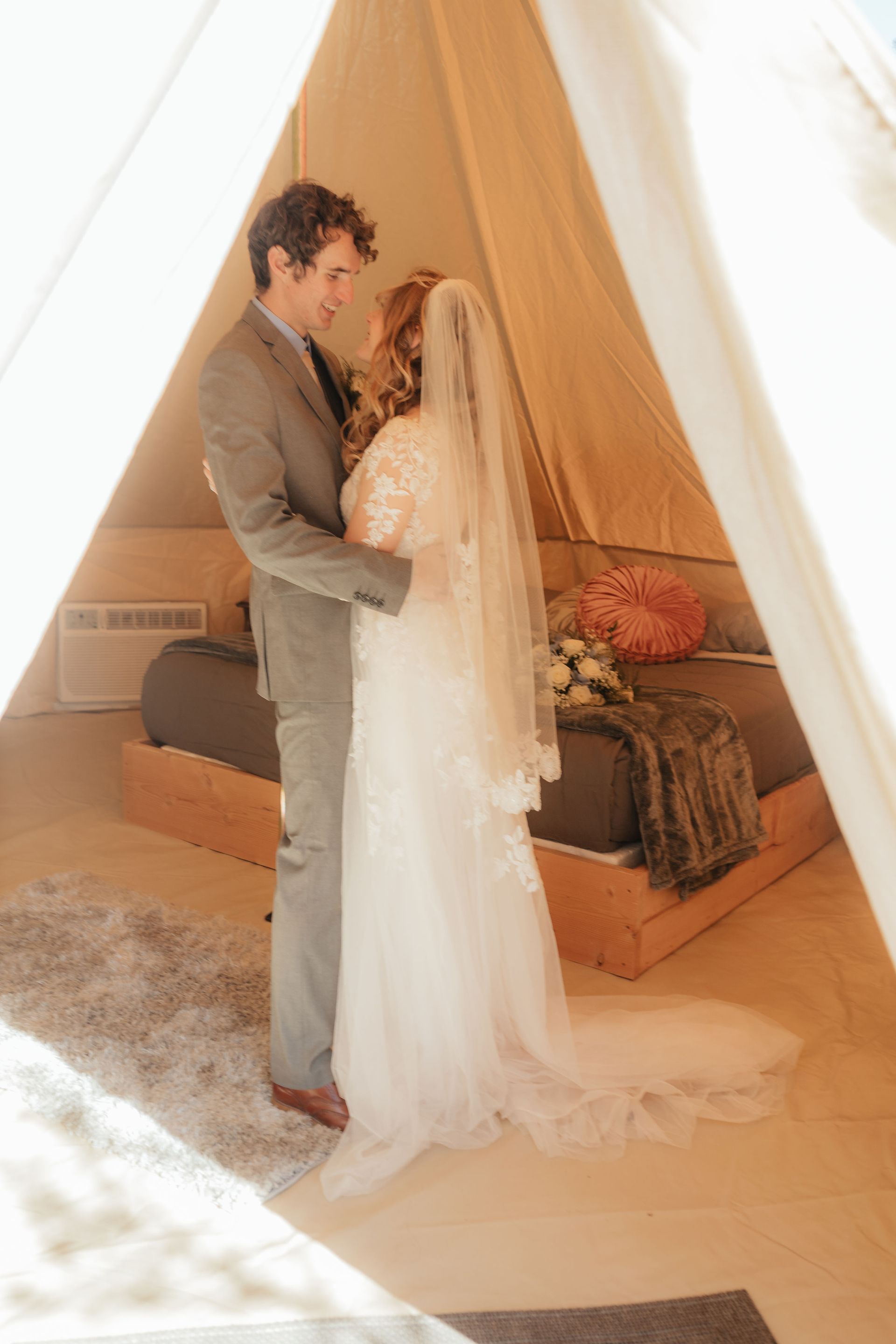 Bride and groom sharing a tender moment inside cozy glamping tent at Zion Glamping Adventures, surrounded by luxurious decor
