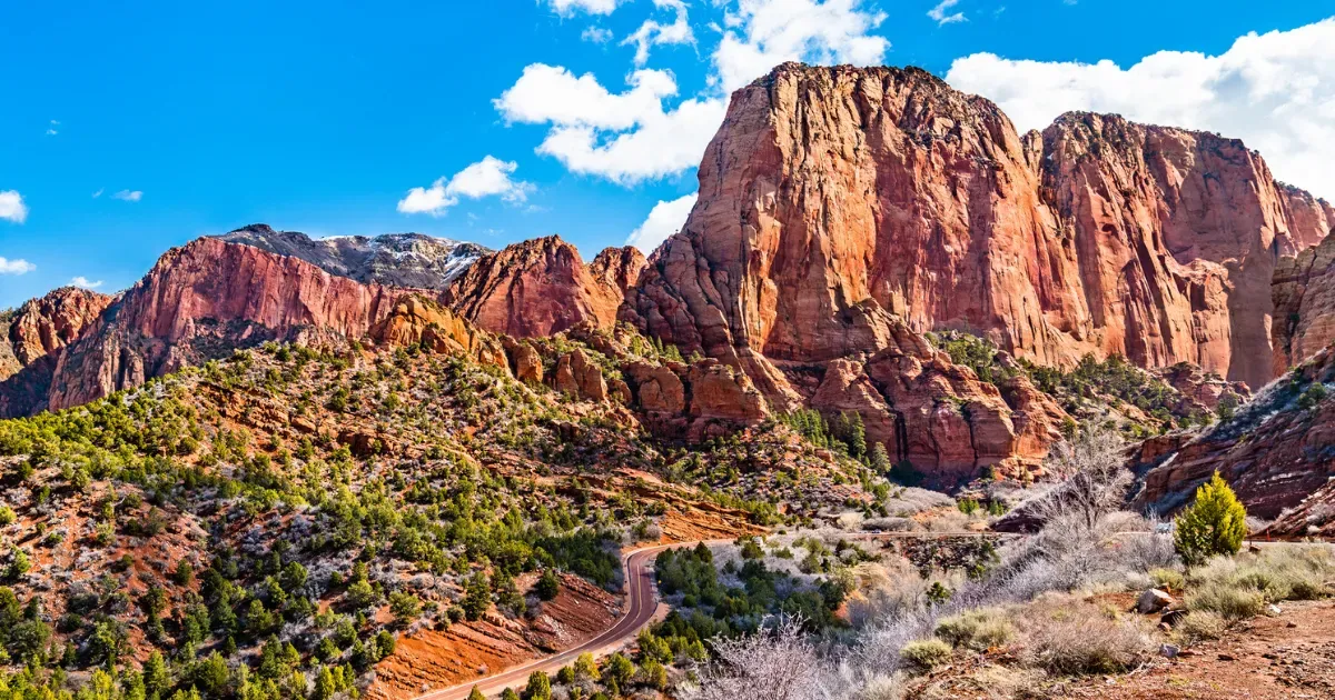 Vibrant, towering red cliffs and a winding road in Kolob Canyons, showcasing the striking natural beauty of the area.