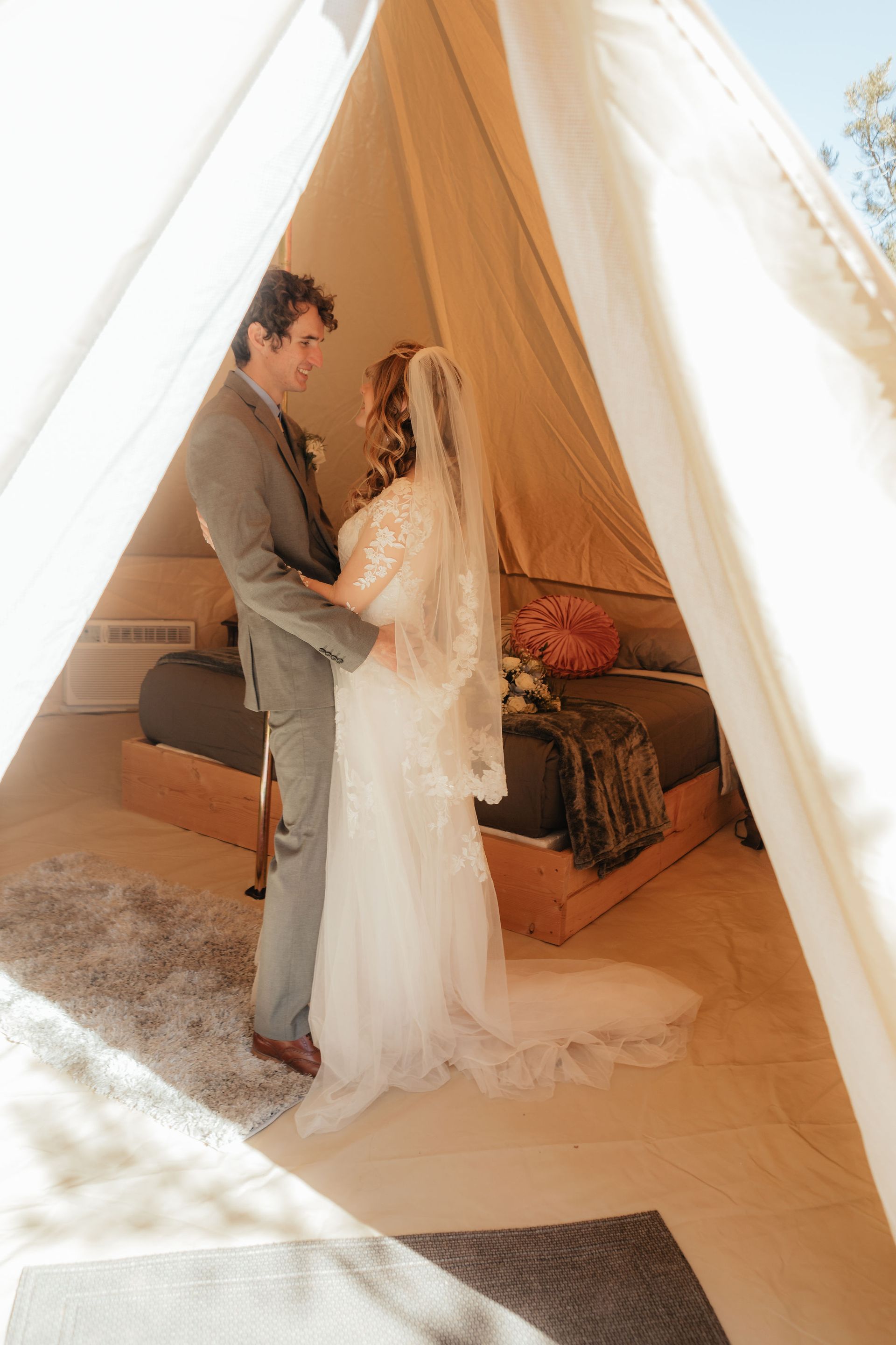 A bride and groom sharing a tender moment inside a glamping tent, highlighting the tent's romantic and elegant setting.