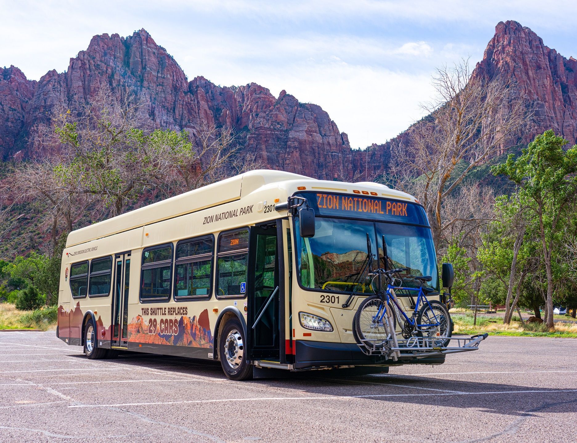 Zion National Park electric shuttle sitting in-front of beautiful red rock landscapes.